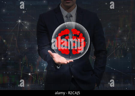 Imprenditore mano che tiene il simbolo del dollaro con icona del cervello al di sopra del grafico di negoziazione sul mercato azionario lo scambio di informazioni di sfondo, salute business Foto Stock