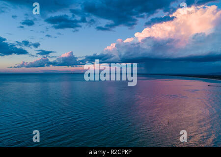 Pioggia e nuvole temporalesche in avvicinamento alla fascia costiera sull'oceano e il bellissimo tramonto - vista aerea Foto Stock