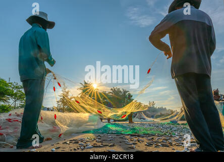 I pescatori stanno facendo la rete di pesca dopo la cattura come un modo di vivere nel villaggio costiero di pesca. Questo è duro lavoro, ma molte famiglie a Phan Thiet, Foto Stock