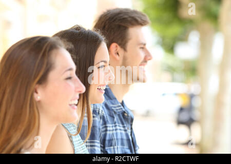 Profilo di tre amici felici che guarda lontano in strada Foto Stock