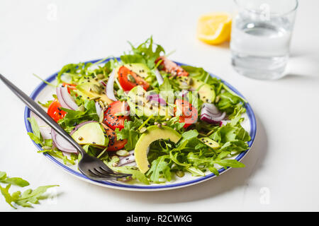 Rucola sani, avocado, insalata di pomodori su marmo bianco dello sfondo. Impianto basato dieta concetto. Foto Stock