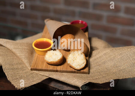 Risotto fritto sfere servita su legno con muro di mattoni in background Foto Stock