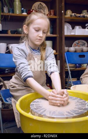 Laboratorio di ceramica - la ragazza fa un vaso di argilla su un tornio del vasaio Foto Stock