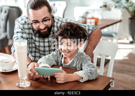 Padre e figlio sensazione divertirsi a giocare con lo smartphone Foto Stock