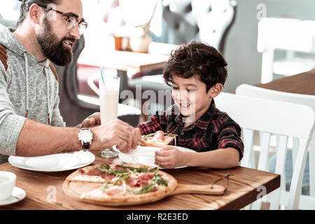 Padre e figlio avente una gustosa pizza per pranzo il fine settimana Foto Stock