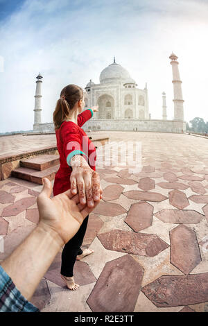 Woman in Red costume indiano azienda man a mano e che puntano al Taj Mahal di Agra, Uttar Pradesh, India Foto Stock