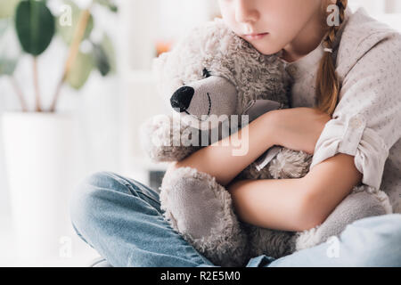 Ritagliato colpo di premuto bambino abbracciando il suo orsacchiotto Foto Stock