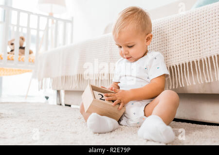 Bimbi adorabili con cubetti di giocare seduto nella nursery room Foto Stock