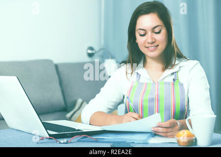 Giovane donna navigando attraverso utili suggerimenti per la cottura in Internet Foto Stock