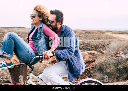 Adulto felice caucasici, giovane divertendosi con la bicicletta nel tempo libero attività. concetto di active giocoso persone con bici durante le vacanze - gioia quotidiana Stile di vita senza limitazioni di età - portare l uomo donna e tanto divertimento e ridere un sacco con il vento in aria Foto Stock