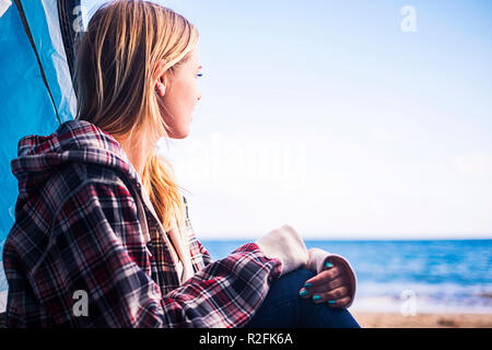 Forme alternative di vita e il concetto di vacanza per bionda ragazza carina sedersi guardando l'oceano sulla porta della sua tenda. Tenerife locetion. Foto Stock