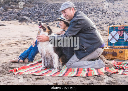 Libertà e tempo libero pic nic attività sulla spiaggia per una alternativa famiglia gruppo di amici due persona e un bel cane. Tutti hanno divertimento outdoor in vacanza Foto Stock