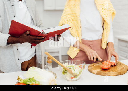 Vista ritagliata di interracial giovane cucinare la cena insieme in cucina Foto Stock