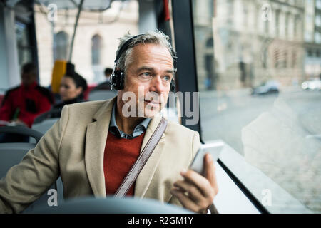 Coppia stanco imprenditore con cuffie e smartpone viaggiare in autobus in città. Foto Stock