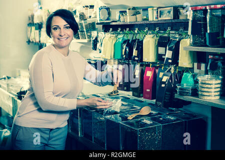 Positivo bruna matura donna scelta di tè venduti a peso in organico negozio Foto Stock