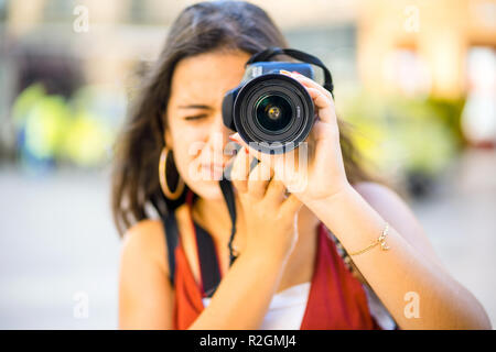 Bella adolescente con lunghi capelli scuri si concentra sulla fotografia tenendo in ambiente urbano scenic Foto Stock