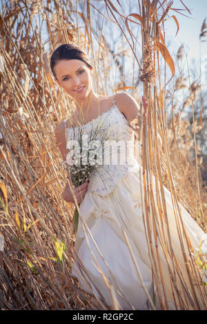 Outdoor ritratto di una sposa con bouquet nuziale in un abito da sposa Foto Stock