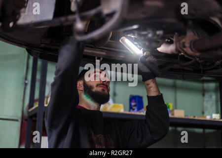 Giovane uomo caucasico riparazione auto con strumenti professionali Foto Stock