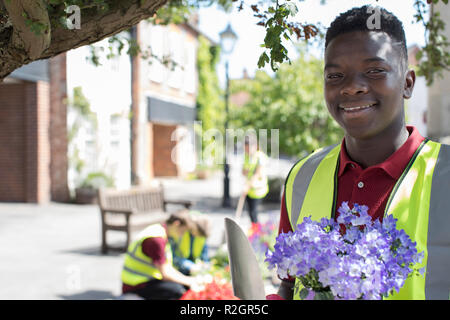 Gruppo di adolescenti utile piantagione e riorganizzati comunale letti di fiori Foto Stock