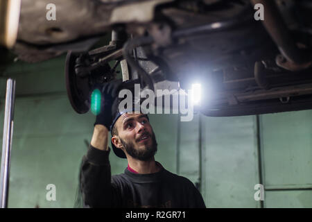 Giovane uomo caucasico riparazione auto con strumenti professionali Foto Stock