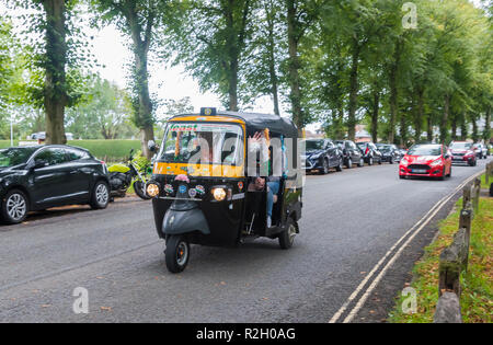 Le persone aventi una gita in un Piaggio Ape City 3 carrello a ruote (comunemente noto come un Tuk Tuk Veicolo) da Arundel, West Sussex, Regno Unito. Foto Stock
