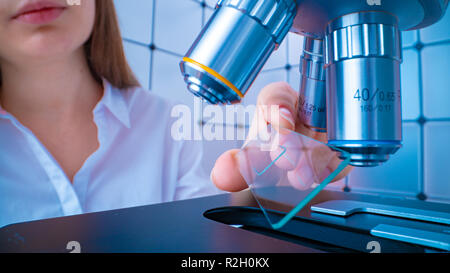 Scienziato analizzando vetrino del microscopio in laboratorio. Giovane donna tecnico sta esaminando un campione istologico, una biopsia in laboratorio di cancro ri Foto Stock