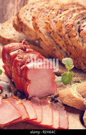 Vetri fatti in casa prosciutto affumicato con fresche erbe aromatiche e spezie aromatiche, close up vista vintage Foto Stock