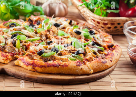 Pizza piccante con pollo gyros, peperone verde, olive e cipolla sul tagliere Foto Stock