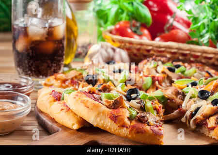 Pizza con pollo gyros, peperone verde, olive e cipolla sul tagliere. Servita con cola Foto Stock