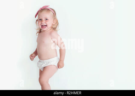 Baby girl nel pannolino ride felice guardando la telecamera Foto Stock