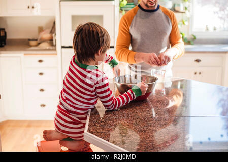 Ragazzo aiutando il padre cuocere in cucina Foto Stock