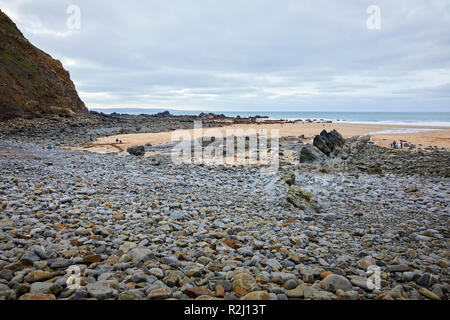 I vacanzieri su un giorno nuvoloso con la bassa marea sulla baia Duckpool. Bude, Cornwall Foto Stock