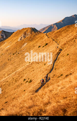 L uomo e la donna in mountain bike nelle alpi austriache al tramonto vicino a Gastein, Salisburgo, Austria Foto Stock