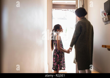 Affettuosa madre e figlia per mano nella porta Foto Stock