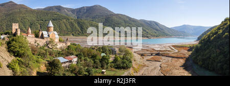 Vista panoramica della fortezza di Ananuri, fiume Aragvi e Zhinvali serbatoio in autunno. Basso livello dell'acqua e visibili in stile georgiano vecchia strada militare, di solito flo Foto Stock