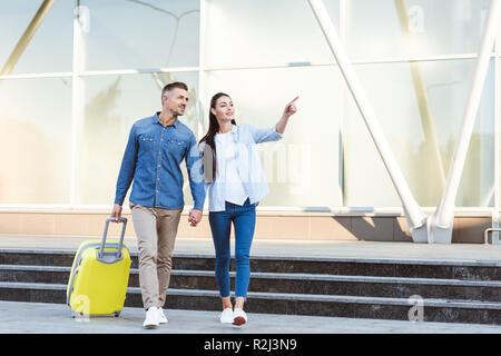 Un paio di turisti Holding Hands, sorridente, che guarda lontano e che puntano a qualcosa di Foto Stock