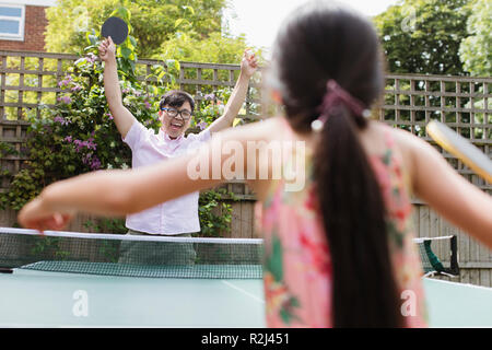 Esuberante padre e figlia giocando a ping-pong Foto Stock