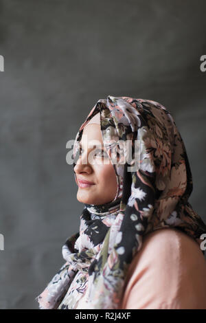 Serena, premurosa donna in floral hijab cercando Foto Stock