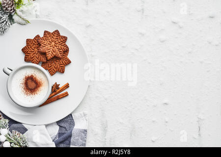 Gingerbread cookies con cioccolata calda bevanda o zabaione su un piatto di portata su marmo bianco tabella coperta di neve. Vista superiore del tradizionale Natale gin Foto Stock