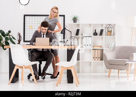 Imprenditrice massaggio a un collega sul posto di lavoro in ufficio, ufficio concetto romantico Foto Stock