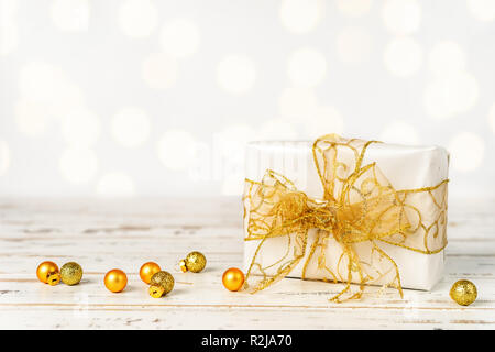 Bianco Natale confezione regalo con un grande arco d oro su sfondo bianco. Spazio di copia Foto Stock