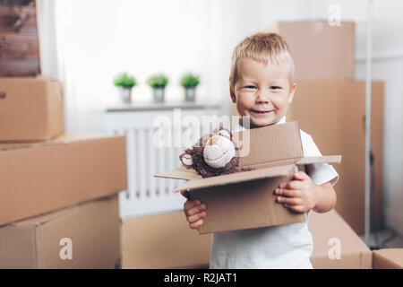 Carino il toddler aiutando le scatole da imballaggio e spostamento Foto Stock