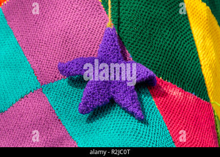 Close up viola stella di Natale fatti di lana con sfondo patchwork Foto Stock