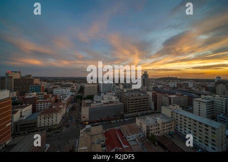 Un tramonto è visto oltre il Harare skyline della città in Zimbabwe Foto Stock