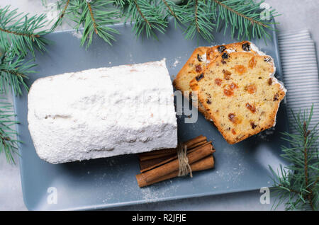 Frutta e dado di torta di pane spolverata con zucchero a velo, le vacanze di Natale ed invernali trattare, torte fatte in casa con uvetta su sfondo grigio Foto Stock