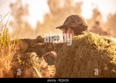 Sniper armati di grande calibro, il fucile da cecchino, tiro bersagli nemici sul campo da riparo, seduta in agguato Foto Stock