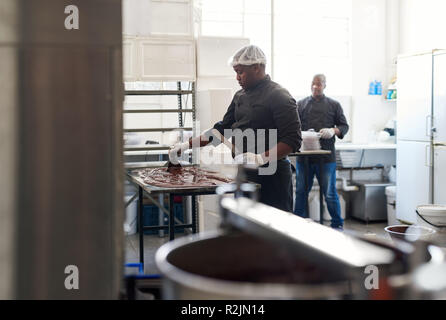 Lavoratore di cioccolato di raffreddamento in una confetteria rendendo la fabbrica Foto Stock