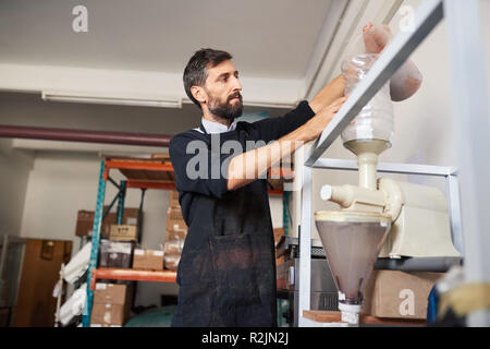 La produzione del cioccolato operaio di fabbrica mettendo le fave di cacao in una macchina Foto Stock