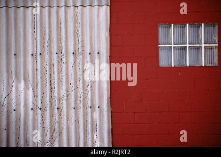 Close-up di una finestra realizzata delle mattonelle di vetro ad un rosso-parete dipinta con annesso ferro corrugato, Foto Stock