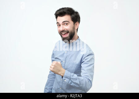 Il successo emozionale ispanica giovane uomo con i capelli scuri urlando sì e sollevamento di pugno chiuso. Foto Stock
